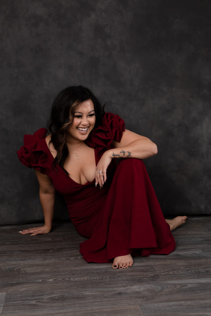 confident woman sitting on floor laughing in evening gown